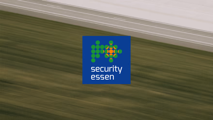 The Security Essen trade fair logo over an aerial view of open farmland.